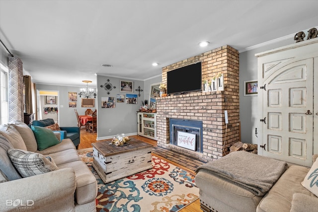 living room featuring a fireplace, hardwood / wood-style flooring, an inviting chandelier, and ornamental molding