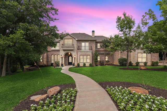 view of front of house with a balcony and a yard