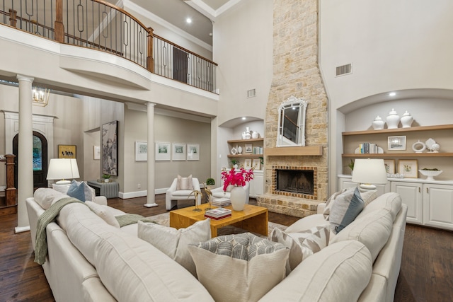 living room with a high ceiling, dark hardwood / wood-style flooring, a stone fireplace, and built in shelves