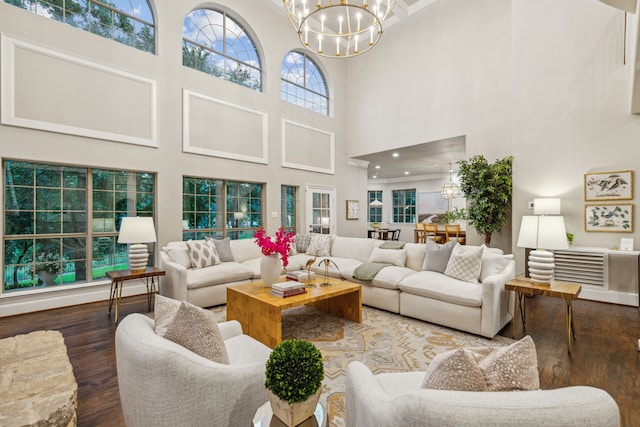 living room featuring a towering ceiling, dark wood-type flooring, and an inviting chandelier