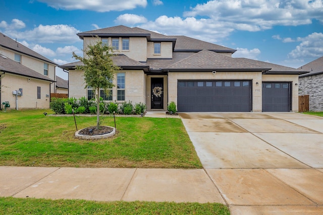 prairie-style house featuring a garage and a front lawn