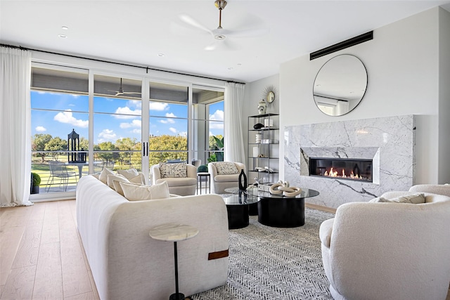 living area featuring a high end fireplace, ceiling fan, and hardwood / wood-style flooring