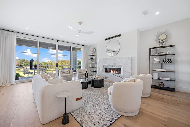 living area with recessed lighting, a premium fireplace, a ceiling fan, visible vents, and light wood finished floors