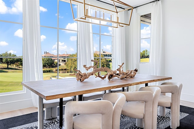 dining space with baseboards, wood finished floors, and an inviting chandelier