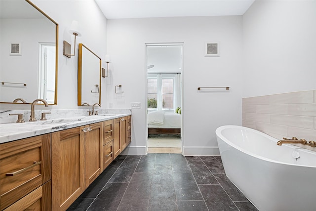 ensuite bathroom featuring connected bathroom, a freestanding tub, a sink, and double vanity