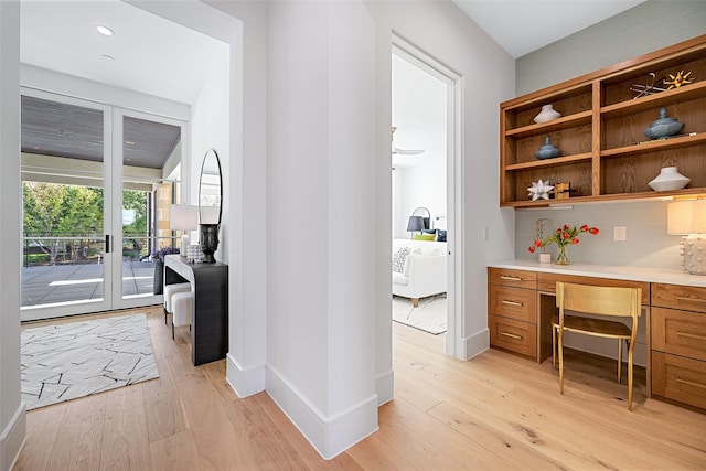 interior space with built in desk, light wood-style flooring, and baseboards