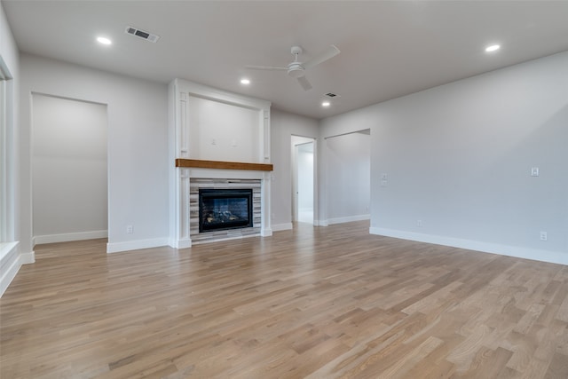 unfurnished living room with a fireplace, ceiling fan, and light hardwood / wood-style flooring