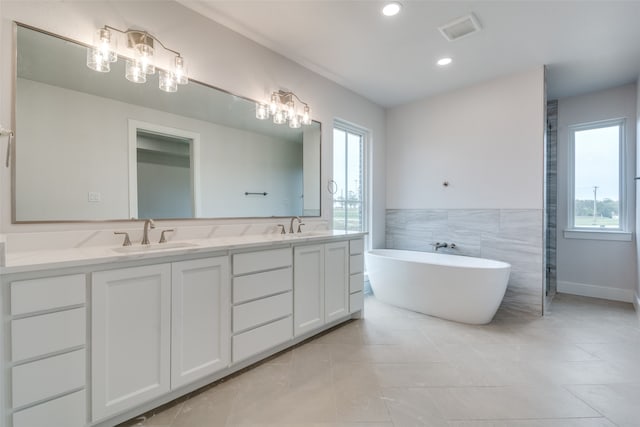 bathroom featuring a tub to relax in, tile patterned floors, vanity, and tile walls