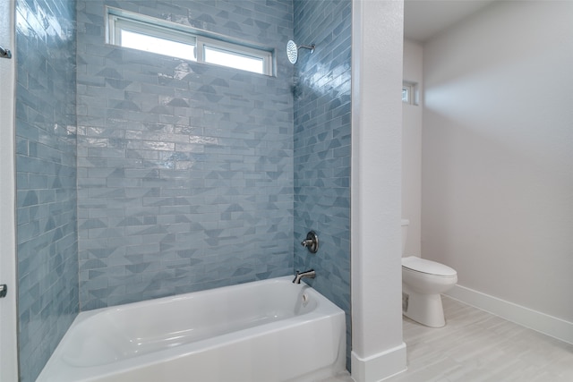 bathroom featuring tiled shower / bath combo and toilet