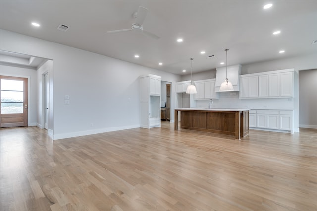 unfurnished living room with light wood-type flooring, ceiling fan, and sink