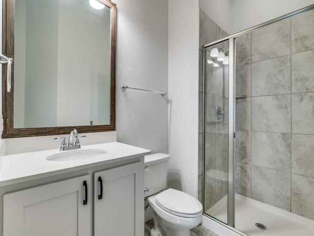 bathroom with a shower with shower door, vanity, and toilet