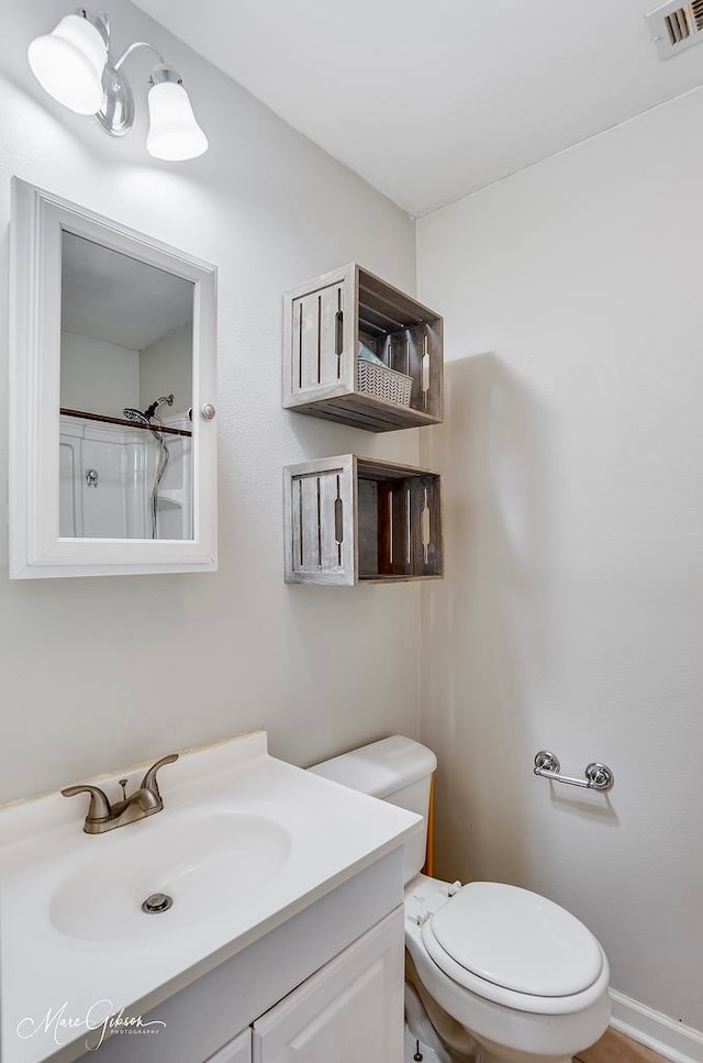 bathroom with toilet, a shower, and vanity