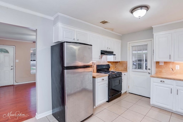 kitchen with a healthy amount of sunlight, black gas stove, stainless steel fridge, and white cabinets