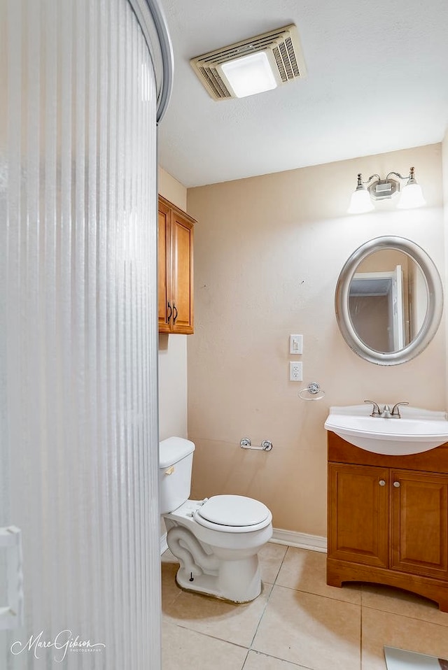 bathroom with toilet, vanity, and tile patterned floors