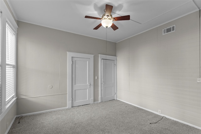 unfurnished bedroom featuring multiple windows, carpet, and ceiling fan