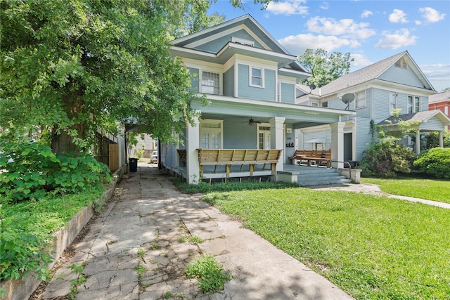 victorian home with a front lawn, ceiling fan, and covered porch