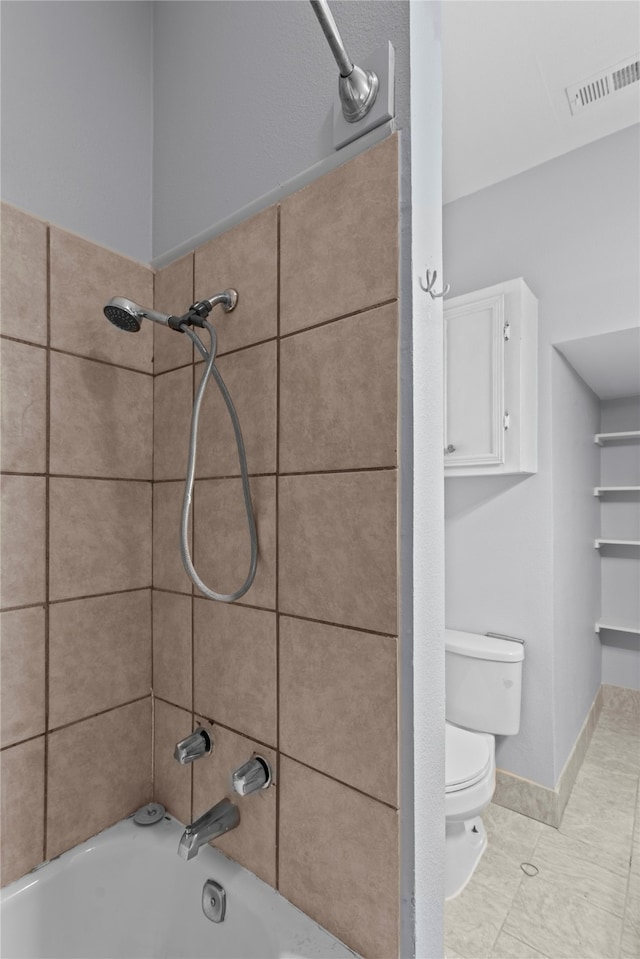 bathroom with tile patterned flooring, tiled shower / bath, and toilet