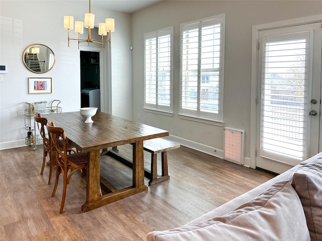 dining space with radiator heating unit, hardwood / wood-style flooring, washer / dryer, and a chandelier