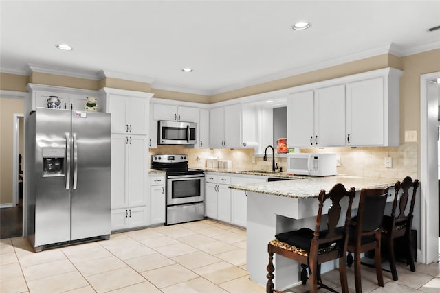 kitchen with white cabinetry, kitchen peninsula, appliances with stainless steel finishes, and a kitchen bar