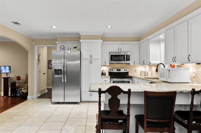 kitchen with stainless steel appliances, light hardwood / wood-style floors, white cabinetry, light stone countertops, and crown molding