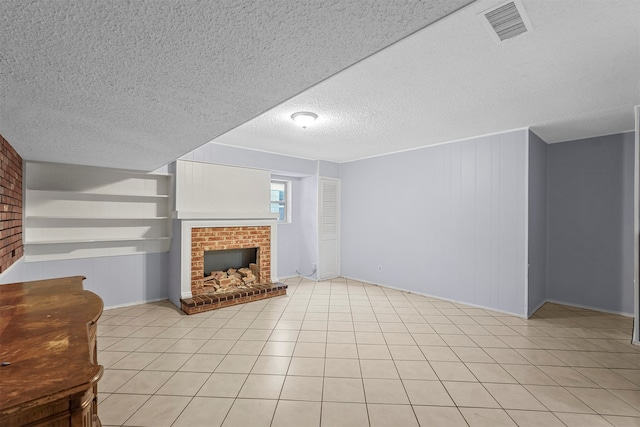 unfurnished living room with wooden walls, a textured ceiling, light tile patterned floors, and a brick fireplace