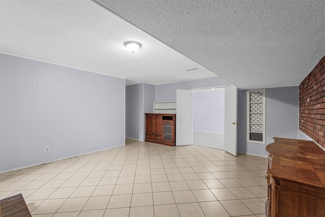 unfurnished living room with wood walls, a textured ceiling, and light tile patterned floors