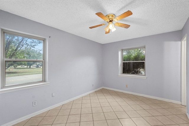 tiled empty room featuring ceiling fan, a textured ceiling, and a healthy amount of sunlight