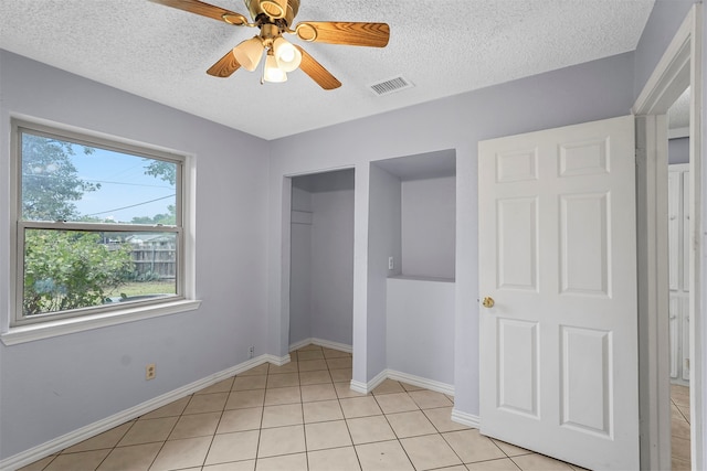 unfurnished bedroom featuring a textured ceiling, ceiling fan, and light tile patterned floors