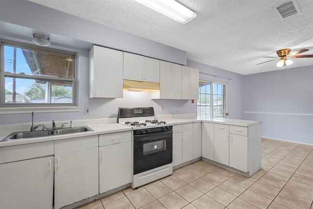 kitchen featuring gas range gas stove, kitchen peninsula, sink, and white cabinets