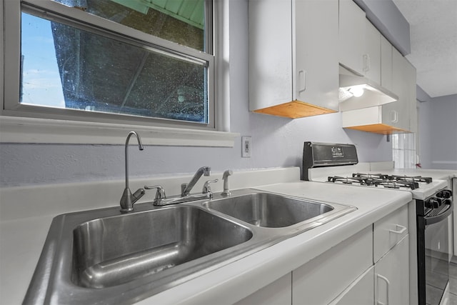 kitchen with tile patterned flooring, sink, white gas range, and white cabinets