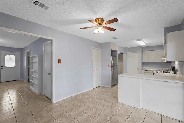 kitchen with stainless steel appliances, ceiling fan, a textured ceiling, and kitchen peninsula