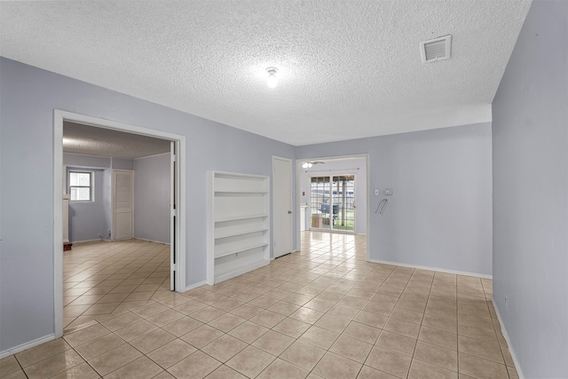 tiled empty room featuring plenty of natural light and a textured ceiling