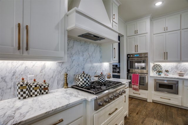 kitchen featuring light stone counters, stainless steel appliances, white cabinets, dark wood-type flooring, and custom exhaust hood