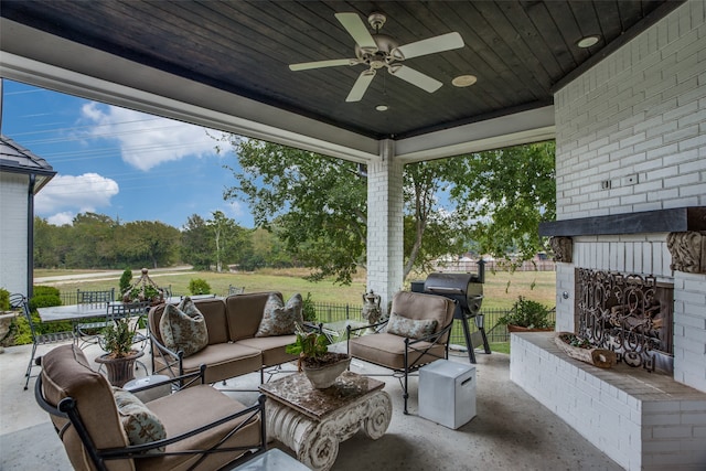 view of patio / terrace with ceiling fan and an outdoor living space with a fireplace