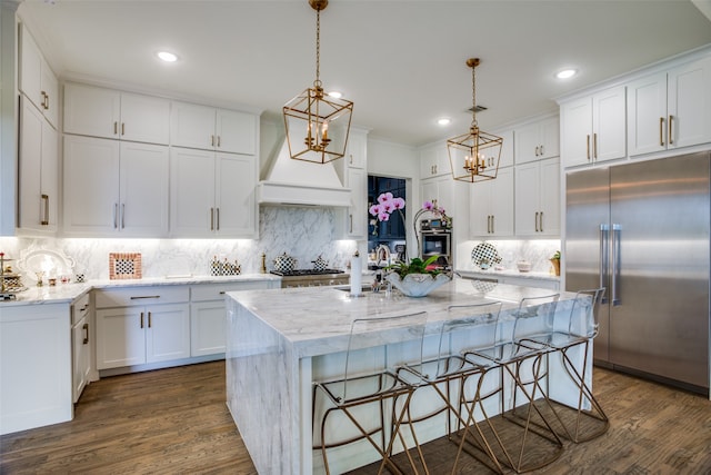 kitchen with white cabinets, stainless steel appliances, a kitchen island with sink, and dark wood-type flooring