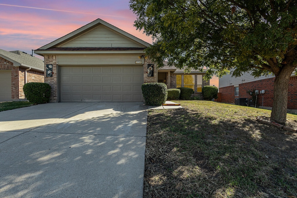 ranch-style home with a garage and a yard