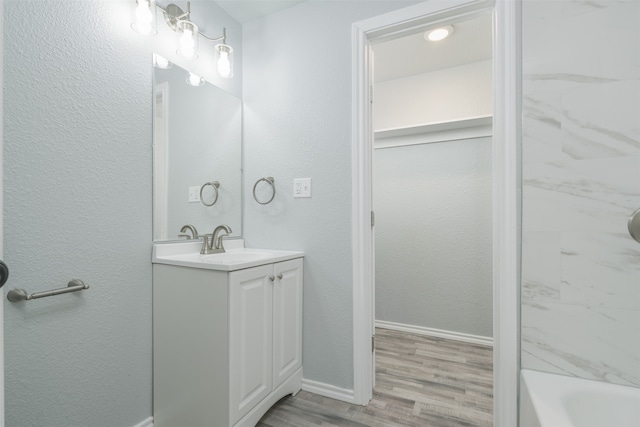 bathroom with tiled shower / bath combo, vanity, and wood-type flooring