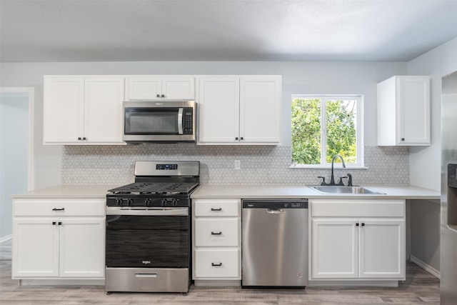 kitchen with white cabinetry, sink, appliances with stainless steel finishes, light wood-type flooring, and decorative backsplash