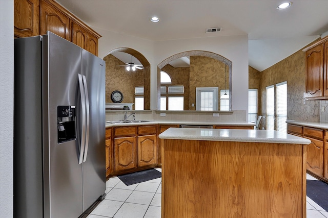 kitchen with light tile patterned flooring, stainless steel fridge, sink, ceiling fan, and a center island