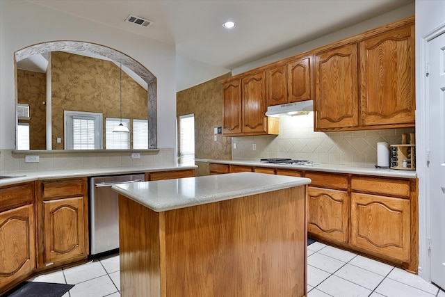 kitchen with stainless steel appliances, a center island, decorative backsplash, light tile patterned floors, and decorative light fixtures