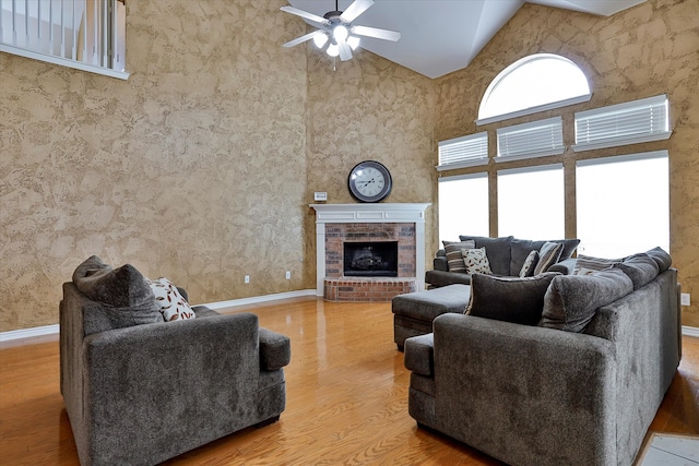 living room with a brick fireplace, high vaulted ceiling, hardwood / wood-style flooring, and ceiling fan