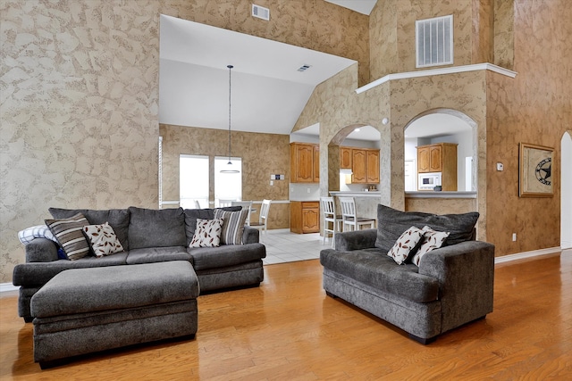 living room with high vaulted ceiling and light hardwood / wood-style flooring