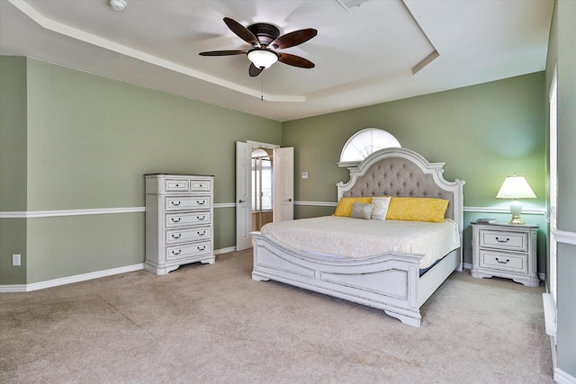 bedroom featuring light carpet, ceiling fan, and a raised ceiling