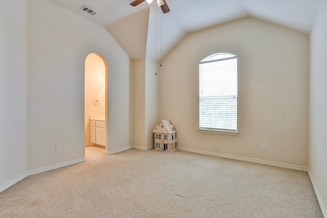 carpeted spare room with ceiling fan and vaulted ceiling