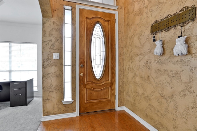 entrance foyer with ornamental molding, a wealth of natural light, and hardwood / wood-style flooring