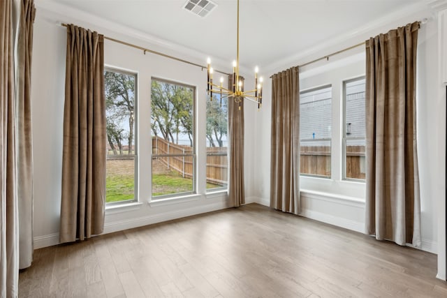 unfurnished dining area featuring light hardwood / wood-style floors, a healthy amount of sunlight, and crown molding