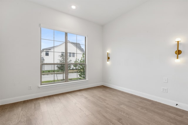 empty room with a wealth of natural light and light hardwood / wood-style flooring