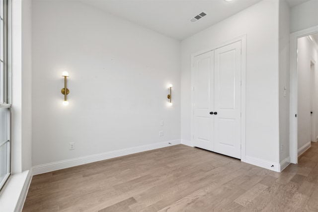 unfurnished bedroom with light wood-type flooring and a closet