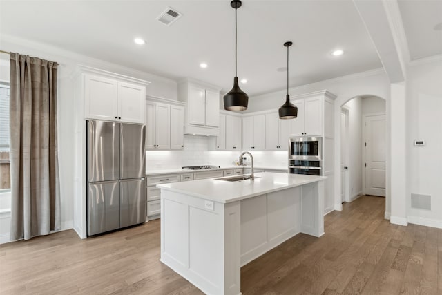 kitchen with white cabinetry, sink, hanging light fixtures, stainless steel fridge, and light wood-type flooring