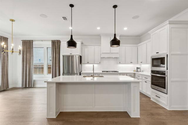 kitchen with white cabinets, sink, appliances with stainless steel finishes, and hardwood / wood-style floors